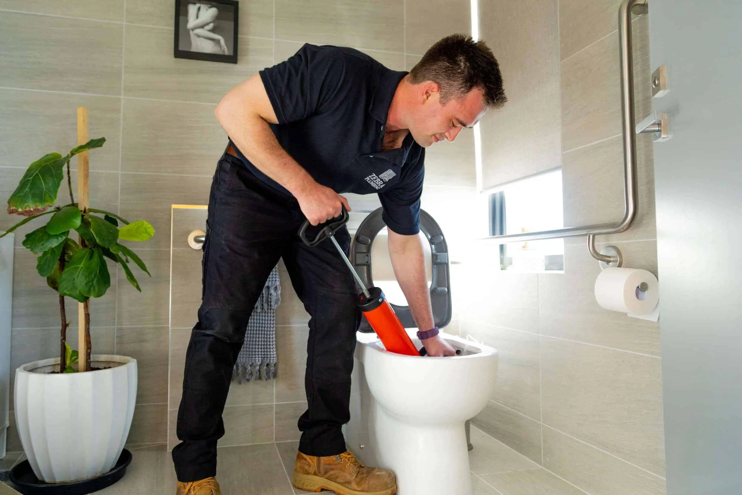 Plumber performing toilet unblocking service in London